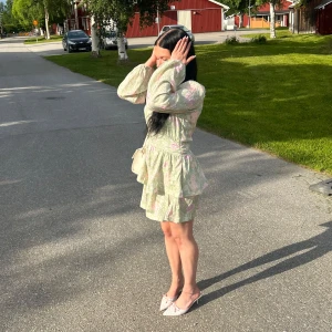 Grön blommig klänning - Supersöt kortklänning i ljusgrönt med blommigt mönster i rosa, lila och beige toner. Klänningen har långa ärmar, v-ringning och volangdetaljer i kjolen. Perfekt för sommarens alla tillfällen och ger en romantisk vibe. Köpt från Bikbok för 699kr, använd en gång på midsommar! 