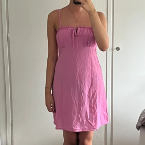 Rosa kortklänning från ONLY - Söt rosa kortklänning från Nelly. Klänningen har smala axelband som kan klippas av för en axelbandslös look, knytning framtill och lätt lös passform. Perfekt för varma dagar och sommarvibbar.