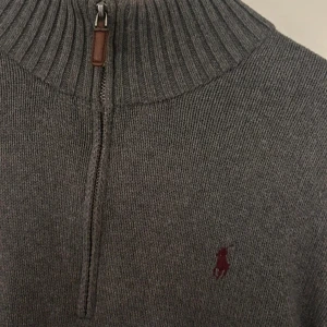 Grå stickad polotröja Polo Ralph Lauren - Snygg grå stickad polotröja från Polo Ralph Lauren med half zip och ribbad krage. Tröjan har lång ärm och den klassiska broderade loggan i vinrött på bröstet. Perfekt för lager-på-lager och chill höst- och vinterstil. Kashmir, nypris 2999kr. 