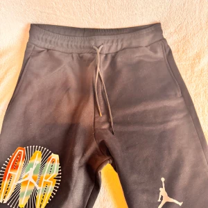 Svarta Jordan shorts  - Snygga svarta och helt nya shorts från Jordan med färgglatt AIR-tryck och klassisk Jumpman-logga. Mjukt material, elastisk midja med snörning och bakficka. Perfekta för träning eller chill. Styla med hoodie eller t-shirt för en sportig vibe. Pris är ej hugget i sten 