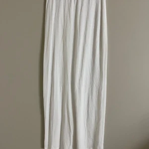 Vit långkjol med slits från Nelly - Supersnygg vit långkjol från Nelly i storlek XS. Kjolen har ett diskret hålstickat mönster i ränder och en slits framtill som ger en extra touch. Perfekt för dig som gillar en clean och fräsch look. Materialet känns mjukt och luftigt.