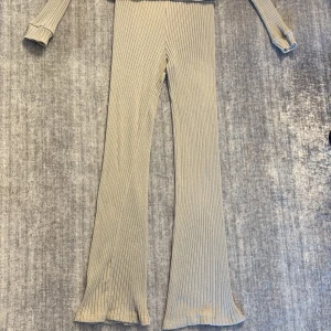  ribbad set - Snygga ribbade byxor i beige med bootcut och hög midja. Byxorna samt tröjan är stretchiga och har en mjuk känsla, perfekta för en chill och trendig look. Passar dig som gillar bekväma men ändå stilrena plagg.