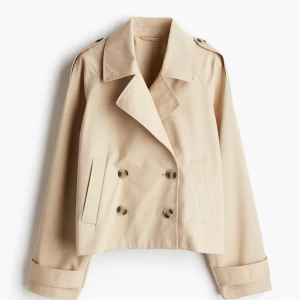 Beige croppad kort trenchcoat med knappar H&M - Så snygg kortare trenchcoat från H&M. Storlek L men sitter snyggt lite oversize på mig som brukar ha storlek xs/s. Nästan aldrig använd. Inga defekter!