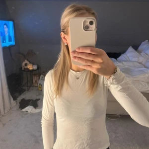 Vit långärmad topp från H&M  - Säljer en enkel och stilren vit långärmad topp från H&M. Modellen är figurnära med rund halsringning.  Perfekt att matcha med jeans eller kjol. 