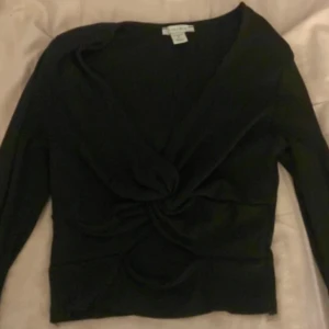 Svart omlottop med twist  - Svart långärmad omlottop från Amisu i ribbad stretchig kvalitet. Snygg twistdetalj framtill som ger en cool look och markerar midjan. Djup v-ringning och figurnära passform, perfekt till jeans eller kjol.