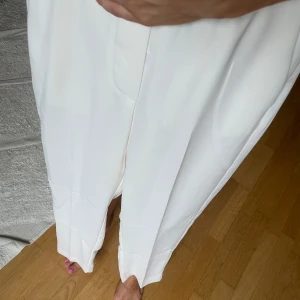 Vita kostymbyxor från Mango XS - Snygga vita kostymbyxor från Mango i storlek XS. Byxorna har raka ben, pressveck och midja med dold stängning. De är tillverkade i ett mjukt, lätt material som ger en clean och fräsch look. Aldrig använda på grund av att de är för små.