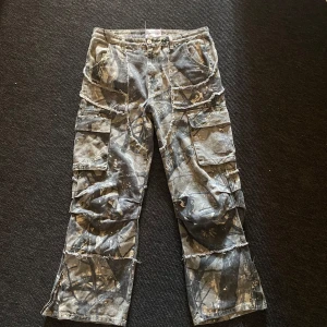 Flared Camo Cargo Jeans - Skogscamo cargos i jeansmaterial med justerbar flare, snygga och unika i bra kvalitet inte från nått märke jag känner igen pris kan diskuteras