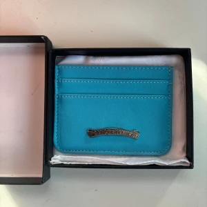 Turkos plånbok från Chrome Hearts - Snygg turkos plånbok från Chrome Hearts i skinn med flera kortfack och cool silverfärgad logga framtill. Kommer i original ask och med vit dustbag. Perfekt för dig som vill ha något unikt och stilrent i fickan.
