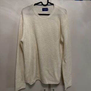 Vit stickad tröja från Jack & Jones - Säljer en stilren vit stickad tröja från Jack & Jones. Tröjan har rund halsringning, lång ärm och ett diskret ribbat mönster. 