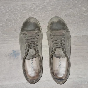 Bruna lanvins - Snygga sneakers från Lanvin i grå mocka med rund tå och platt sula. Skorna har klassisk snörning och en stilren design som passar till det mesta. Perfekta för dig som gillar en clean och avslappnad look. Passar även 43🙌🤩