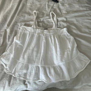 Vit linnetopp - Supersöt vit linnetopp med volangkant nertill. Toppen har en luftig och flowy passform, perfekt för varma dagar. 