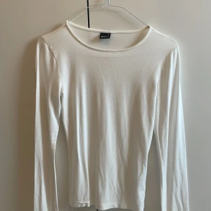Vit långärmad tröja  - Enkel och stilren vit långärmad tröja från Gina Tricot i storlek XS. Tröjan har rund halsringning och är gjord i mjukt bomullsmaterial, perfekt att matcha med jeans eller kjol för en clean look.