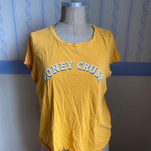Gul t-shirt HONEY CRUSH  - Gul t-shirt från L.O.G.G. med trycket 'HONEY CRUSH' i vitt och svart framtill. Färgen är mer mörk i verkligheten 🩷
