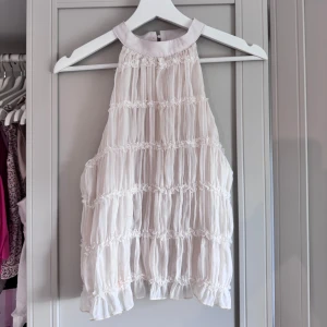 Vit volangig blus med hög hals - Supersöt vit halteneck med hög hals och knäppning bak.