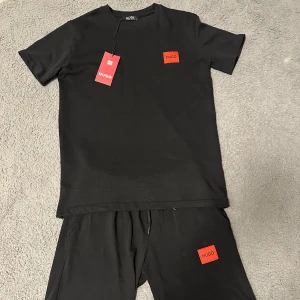 Hugo Boss set  - Svart t-shirt från Hugo Boss med röd HUGO-logga på bröstet. Samma med shortsen. Perfekt till sommaren🌞