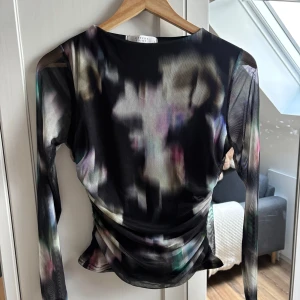 Blus med mönster - Säljer en meshblus från Sisters Point med lång ärm och abstrakt mönster i olika färger. Blusen är figurnära med lätt rynkade detaljer i midjan och har en transparent känsla. 