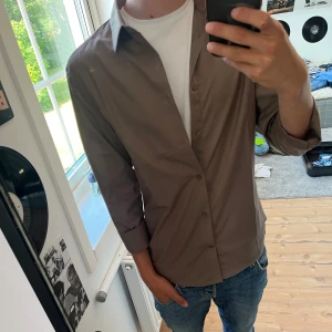 Beige skjorta med klassisk krage - Säljer en stilren beige skjorta från hm som är i storlek S och slim fit. Använd 1 gång, snygg och passar perfekt till dig som är runt 170-175cm. Nypris runt 150kr mitt pris 75