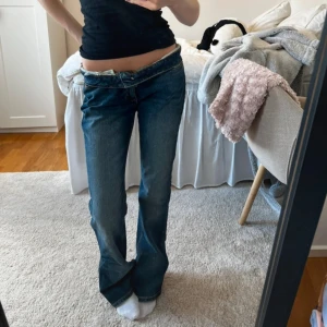 Lågmidjade blå bootcut jeans - Säljer ett par blå jeans med låg midja och bootcut-ben. Har ett väldigt snyggt mönster på fickorna. 