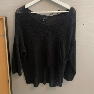 Svart stickad tröja från KappAhl - Svart stickad tröja från KappAhl i loose fit med lång ärm och en stor ficka framtill. Tröjan har en lite transparent känsla tack vare det grovmaskiga materialet och en avslappnad, oversized look. Perfekt att slänga på sig över ett linne eller t-shirt.