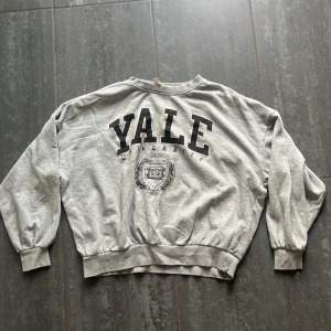 Grå Yale sweatshirt från H&M - Säljer en grå sweatshirt från H&M med stort svart 'YALE University'-tryck framtill. Tröjan har rund hals, långa ärmar med muddar och ribbad nederkant. 