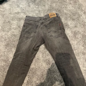 Grå Replay jeans zikry - Snygga grå jeans från Replay med klassisk femficksdesign och slim ben. Jeansen har Replay-logga på bakfickan och patch i läder bak i midjan. Tillverkade i mjukt denimtyg som sitter skönt hela dagen.
