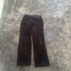 Svarta velourbyxor Juicy Couture XS - Svarta mjukisbyxor från Juicy Couture i velour med snörning i midjan och fickor bak med guldknappar. Byxorna har en relaxed passform och raka ben. Har sur dom men det är inget som syns när men har på sig dom, jag är 160 lång, priset går att prata om 💞