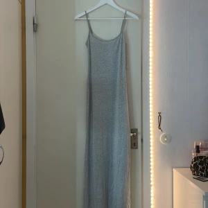 Figursydd tajt långklänning från Gina tricot🤍🤍 - Supersnygg lång grå klänning från Gina Tricot i mjuk bomullsmix. Klänningen har smala justerbara axelband och väldigt tajt mot kroppen. Klänningen är 123cm lång från sido sömmen som börjar vid armhålan. Hyfsat oanvänd och har inga skador🤍🤍🤍.