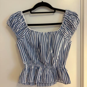 Blåvit randig blus med volang - Supersöt blus i blåvitt randigt med volang nertill och puffiga korta ärmar. Helt ny med prislapp, storlek xxs, perfekt nu till sommaren!! 💕