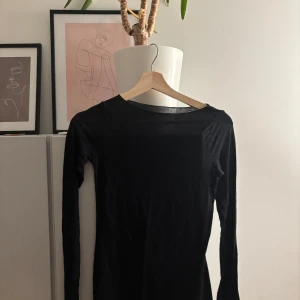 Svart långärmad basic tröja - En svart långärmad tröja i tunn bomull med enkel och stilren design. Tröjan har rund halsringning och en tight passform, perfekt att ha som lager under andra plagg eller till ett par jeans. Enkel och klassisk look som funkar året runt.