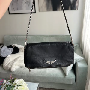 Väska från Zadig&Voltaire - Säljer min fina Zadig&Voltaire väska som använts väl och är i okej skick. Slitage på vissa ställen. Tillkommer långt och kort band. Ett stort, rymligt fack och några mindre fack. Kan användas till vardags eller fest 💖 Älskar denna väska