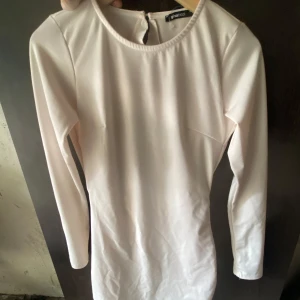 Ljusvit långärmad klänning Gina Tricot - Endast använd en gång !! Supersnygg ljusrosa klänning från Gina Tricot med långa ärmar och en öppen rygg med volangdetalj. Tight passform som framhäver figuren 