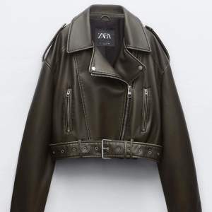 Snygg olivgrön skinnjacka från Zara med dragkedja och bälte i midjan. Jackan är croppad och har långa ärmar samt flera dragkedjefickor framtill. Perfekt för en cool och edgy look!