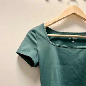 Topp - Grön, kortärmad t-shirt med fyrkantig halsringning från Hollister. Enkel och stilren design. Väldigt mjukt material som påminner om träningsmaterial. Ett måste i garderoben som basplagg. I fint skick, storlek S. Passar också XS. Säljer i andra färger också.🌸