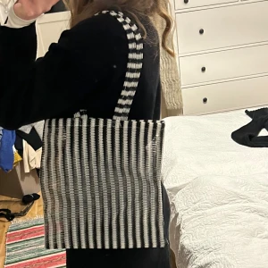 Randig axelväska i svart och vit - See through axelväska med svartvita ränder. Perfekt för att bära med sig det nödvändigaste. Väskan har två handtag som gör den enkel att slänga över axeln.