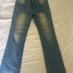 Lågmidjade jeans - Säljer ett par blå jeans med en snygg broderad detalj på bakfickan. Dem är så sjukt snygga, men tyvärr för stora. Helt nya och använda!! Pris kan diskuteras!! Midjemått: ca 41 och innerbenslängd: 84 