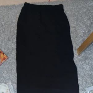 Svart långkjol - Snygg svart kjol med enkel design. Perfekt för en stilren look. Kjolen har en rak passform och går hela vägen ner, vilket gör den mångsidig och lätt att matcha med olika toppar. (Den går hela vägen ner och jag är ungefär 163 cm.)