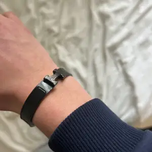 Elegant svart armband med ett stilrent metallspänne. Perfekt för att ge en sofistikerad touch till din outfit.