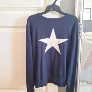 Stickad tröja - Säljer en mörkblå tröja från Gina Tricot med en stor vit stjärna på framsidan. Tröjan har långa ärmar och en rund halsringning. Perfekt för en avslappnad stil. 🟦⭐