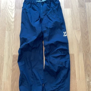 Haglöfs byxor - Säljer ett par svarta täckbyxor från Haglöfs i storlek S. Byxorna har en praktisk dragkedja längs sidan och elastisk midja för extra komfort. Perfekta för utomhusaktiviteter under kalla dagar.