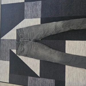 Grå jeansbyxor från jack & Jones - Snygga grå jeansbyxor med en slim passform från jack & jones. De har en klassisk femficksdesign och är perfekta för en stilren look. Midjan är midwaist och byxorna har en dragkedja framtill.