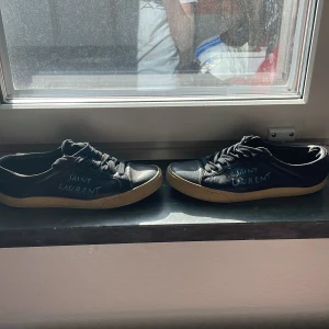 Svarta sneakers från Saint Laurent - Snygga svarta sneakers från Saint Laurent med klassisk design och snörning. Skorna har en diskret logga på sidan och en bekväm gummisula. Perfekta för en stilren look.