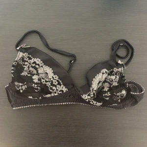 Svart spets-bh med nyckeldetalj Fifty shades of grey Kappahl - Elegant svart bh med vacker spetsdesign och en söt nyckeldetalj vid axelbandet. Den har justerbara axelband och hakknäppning bak för perfekt passform. Perfekt för att känna sig extra fin. Fifty shades of grey kollektion från Kappahl.