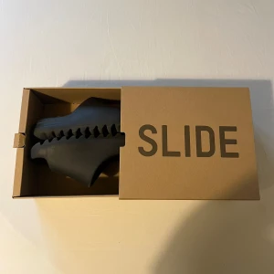 Yeezy slides onyx - Säljer ett par yeezy slides i färgen onyx. Dessa slides är absolut inte de lättaste att få tag på men de är värda varenda krona. Det känns som att man går på moln medans man håller en stilren och casual look. Storleken är 38 men passar mindre och större skulle jag säga då det är tofflor. De har använda och är lite slitna men inte super mycket. Kvitto finns om det önskas jag köpte de personligen av en kille för 1200.Om ni har några frågor eller vill ha mer bilder så va inte rädd för att fråga! 