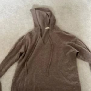 Beige kashmir hoodie - Säljer en mjuk och bekväm grå hoodie från H&M i 100% kashmir. Perfekt för kyliga dagar med sin avslappnade passform och långa ärmar. Huvan har dragsko för justering. Ett måste för garderoben!