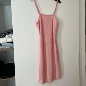 Rosa ärmlös klänning - Säljer en söt rosa klänning med smala axelband. Klänningen har en enkel och stilren design, perfekt för varma dagar. Den är ärmlös och har en rak passform som ger en avslappnad look.💕