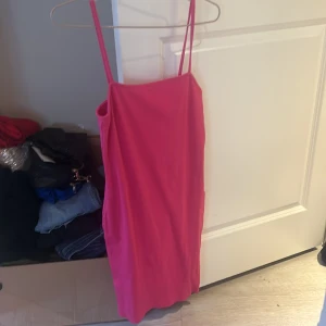 Rosa klänning från Amisu - Säljer en snygg rosa klänning från Amisu med smala axelband. Perfekt för en somrig dag eller kväll. Klänningen har en enkel och stilren design som gör den lätt att matcha med olika accessoarer.
