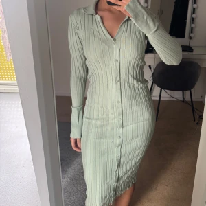 Ljusgrön ribbad klänning - Snygg ljusgrön ribbad klänning med knappar hela vägen ner. Den har långa ärmar och en klassisk krage.