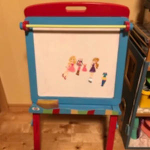 Flerfärgad staffli för barn - Säljer ett färgglatt staffli för barn med en whiteboard tavla på ena sidan och en grön griffeltavla på andra. Staffliet har en röd ram och blå, gröna och röda detaljer. Perfekt för kreativa stunder och lek.