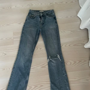 Jeans ginatricot  - Supersnygga jeans ifrån Gina. De är bootcut och mid waist. Har ett hål i ena knäet och lite slitningar ner till. Har använts ca 5 gånger. 
