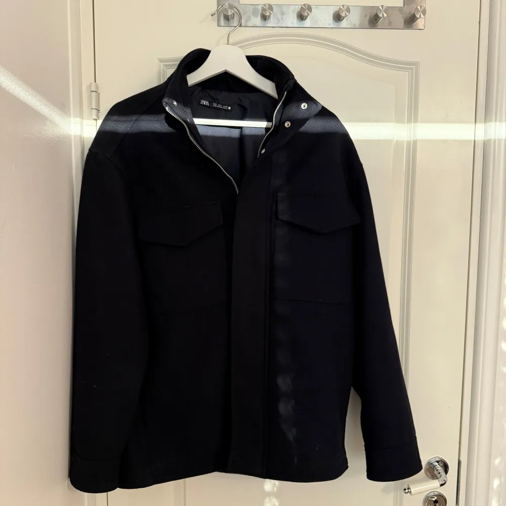 Snygg svart jacka från Zara med dragkedja och knappar. Jackan har långa ärmar och två bröstfickor med lock. Perfekt för en stilren look.. Takit.